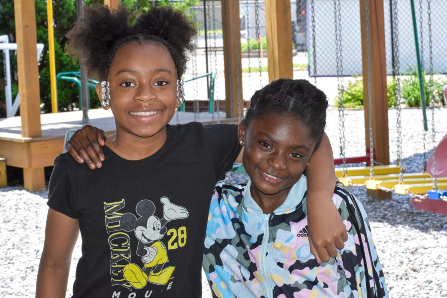 Two young girls with their arms around each other's shoulders
